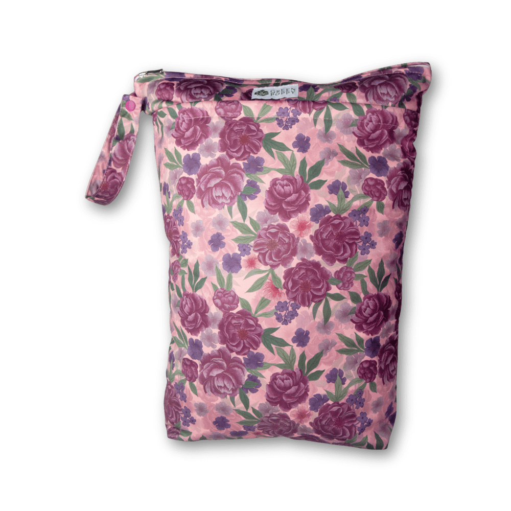en stor påse med ljusrosa bakgrund och mörka lila blommor som print. påsen har en stor öppningsbar ögla på ena sidan och en dragkedja på toppen.