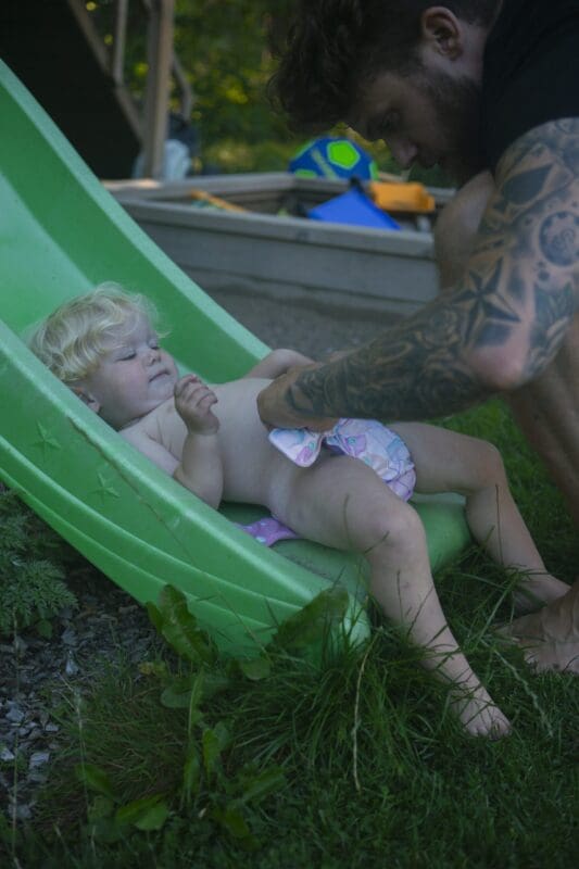 en pappa som byter tygblöja på sitt barn i en lekpark