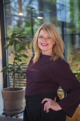 en leende kvinna som står upp och håller en hand i midjan